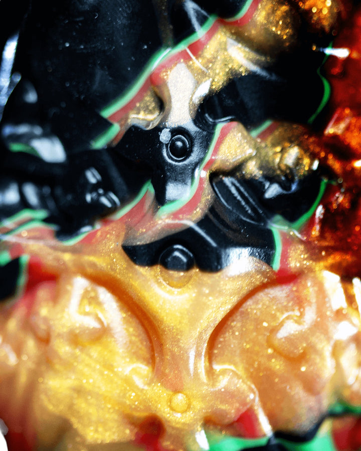 Close-up of Krampus’s ornate collar and circular stud details, with black, red, green and shimmering gold marbling.