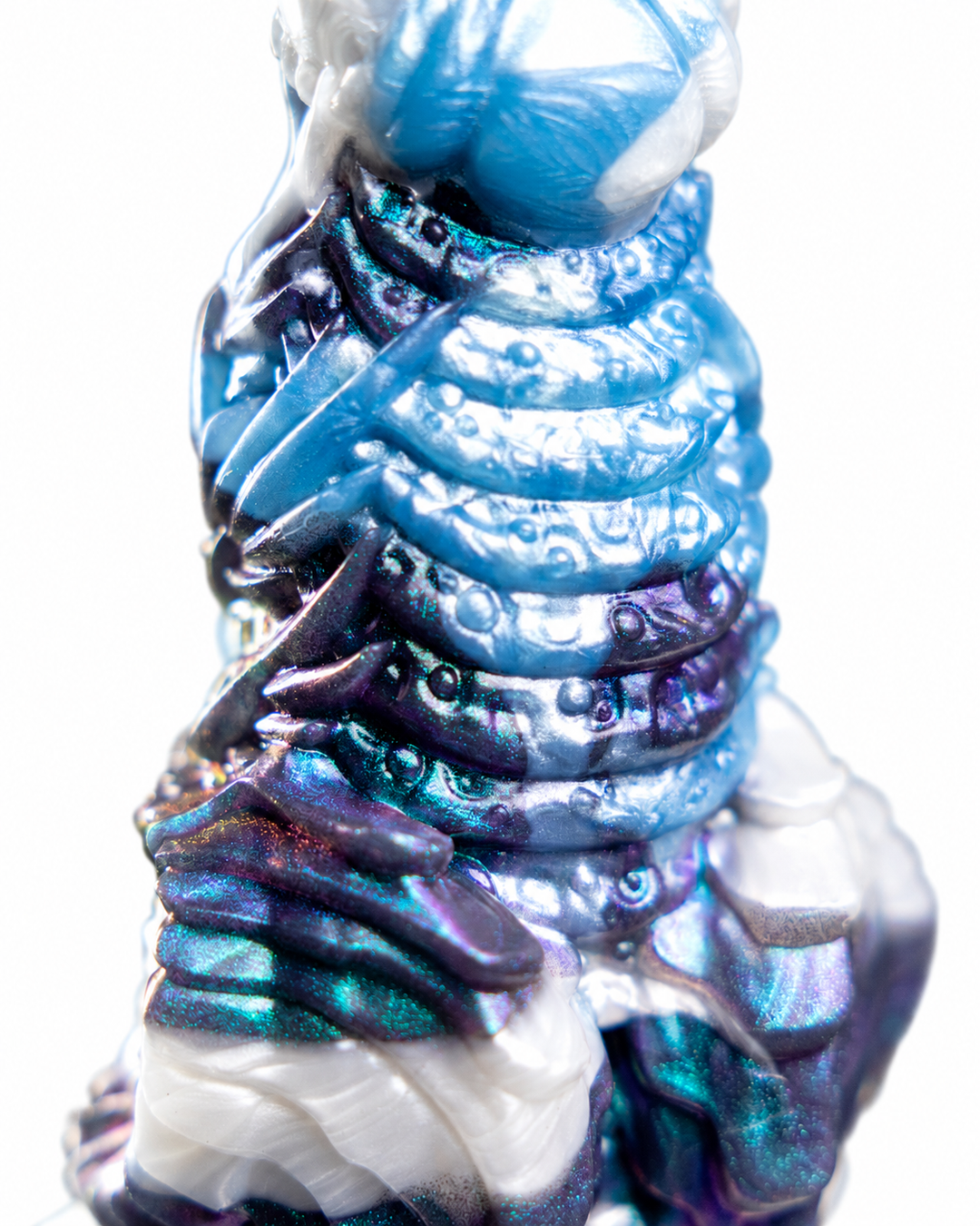 Close-up of Okami’s rounded horizontal ridges and raised circular details, with shimmering blue, white and purple marbling.