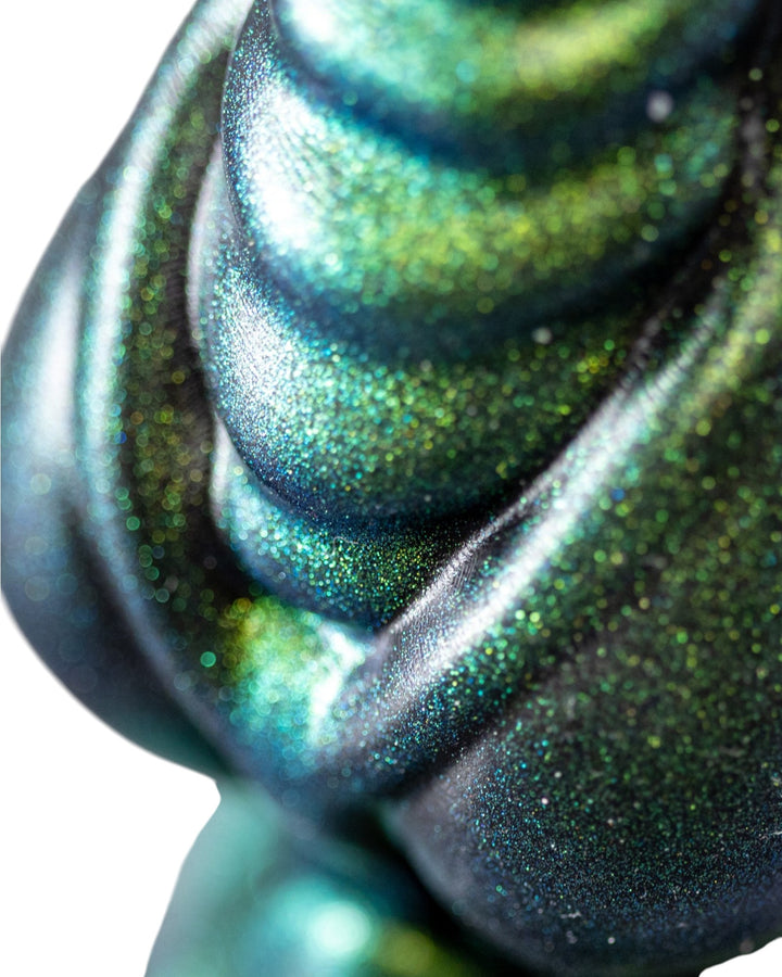 Close-up of rounded ribs and curved detailing on a Phreak silicone toy with an iridescent green and blue finish.